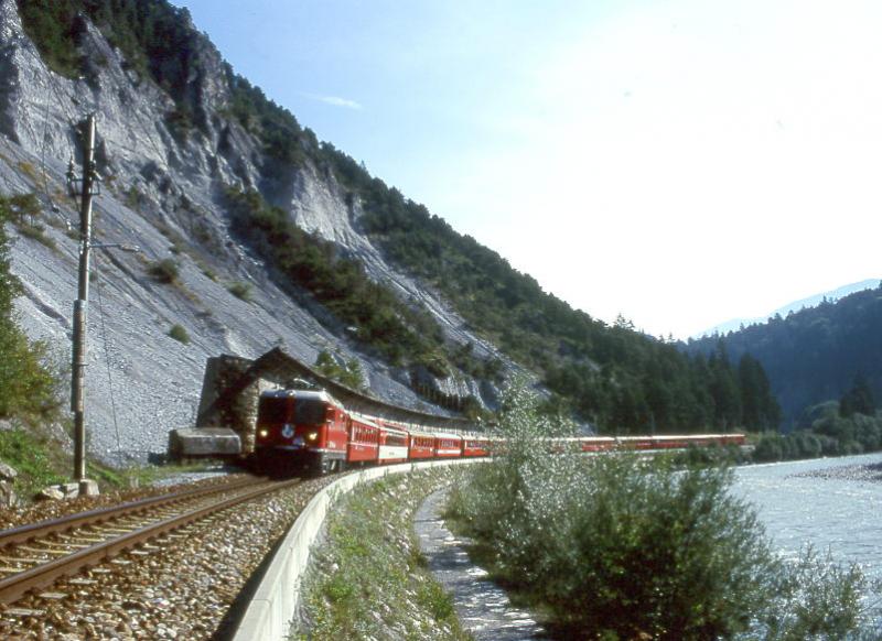RhB Schnellzug GLACIER-EXPRESS G 903 von Davos-Platz nach Zermatt vom 03.09.1997 im Vorderrheintal kurz nach Trin mit E-Lok Ge 4/4II 613 - B 2423 - FO AS 4046 - A 1269 - FO B 4268 - B 2429 - WR 3815 - A(WR-S) 1223 - As 1161 - B 2359 - B 2449 - B 2367 - A 1227 - D 4212. Hinweis: Hier mute beim Bahnbau 1901/1902 der Bahnkrper dem Vorderrhein abgerungen werden. Links vom Zug ist die lange Steinschlagschutzmauer erkennbar.