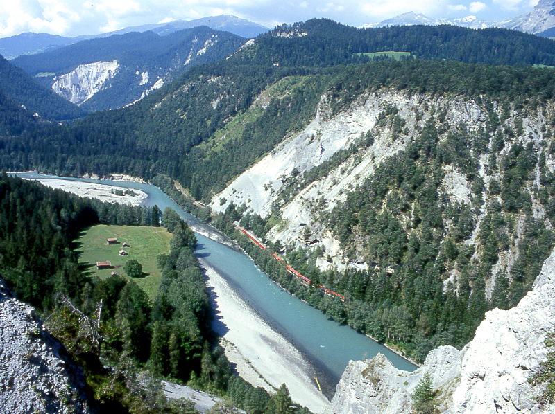RhB Schnellzug GLACIER-EXPRESS K 907 von St.Moritz nach Zermatt vom 25.08.1997 tief unten in der Vorderrheinschlucht im Bergsturzgebiet Ruinaulta bei Isla-Davos mit Ge 4/4II. Hinweis: Auch die Abbruchkante im Vordergrund besteht aus Schuttmasse des gewaltigen Bergsturzes von der gegenberliegenden Talseite! Um die Dimensionen zu verdeutlichen, der Zug ist ber 200 m lang, Entfernung des Rheinknie ist 1 km, Bergsturzabbruchkante links oben ist genau 4 km.