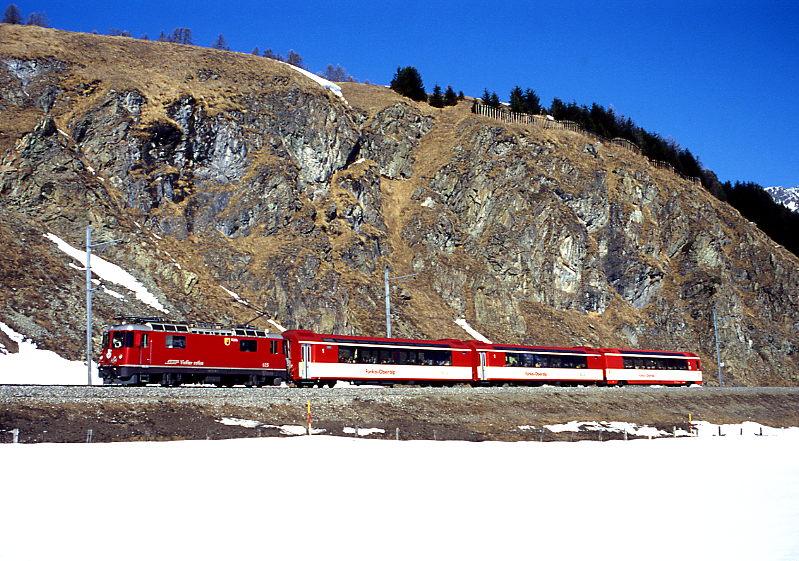 RhB Schnellzug WINTER-PANORAMIC-EXPRESS 101 von Davos-Platz ber Albula nach St.Moritz am 26.02.1998 kurz vor Celerina mit E-Lok Ge 4/4II 625 - FO PS 4014 - FO PS 4011 - FO AS 4021ff. Hinweis: dieser Zug verkehrte als 2.Klasse nur am 29.12.-31.12.1997 und jeweils Dienstag bis Donnerstag vom 20.01.-12.03.1998. Die Kompo lief als Kurswagen von Landquart bis Davos-Platz mit Zug 25. Die Wagen standen im Winter der RhB als Kilometerausgleich fr die Sommer-Glacier-Expresse zur Verfgung und standen in der restlichen Zeit als Verstrkungswagen 1.Klasse im Einsatz. Um an schwachen Verkehrstagen die Wagen sinnvoll fr Mehreinnahmen einzusetzen, wurde der Winter-PANORAMIC-Express als 2.Klasse-Zug eingefhrt. Die Fotostelle ist von Celerina aus leicht in 10 Minuten erreichbar, den Wanderweg der Bahnlinie entlang Richtung Samedan 