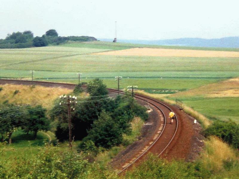 Richtung Grvenwiesbach durchquert die Strecke schwieriges Gelnde einen tiefen S-frmigen Einschnitt, um dann auf offenem Feld und hohem Bahndamm abermals eine 180 Grad Kehrtwendung zu vollziehen, 1. Hlfte der 1980iger Jahre.