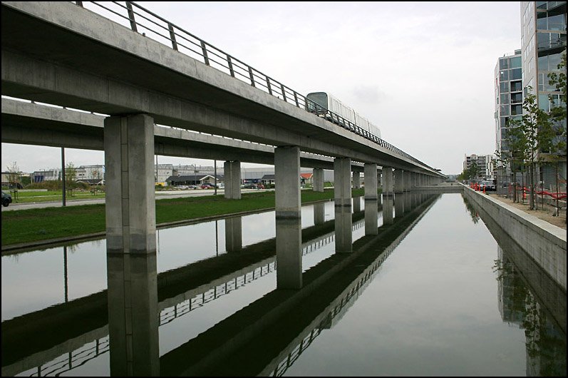 Seit 2002 fährt in Kopenhagen eine vollautomatische, fahrerlose Metro. Der südliche Abschnitt der Linie M1 verläuft teilweise aufgeständert und erschließt das Entwicklungsgebiet Ørestad auf der Insel Amager. Die Aufnahme zeigt den Hochbahnabschnitt zwischen den Stationen Ørestad und Bella Center. 

27.08.2006 (M)