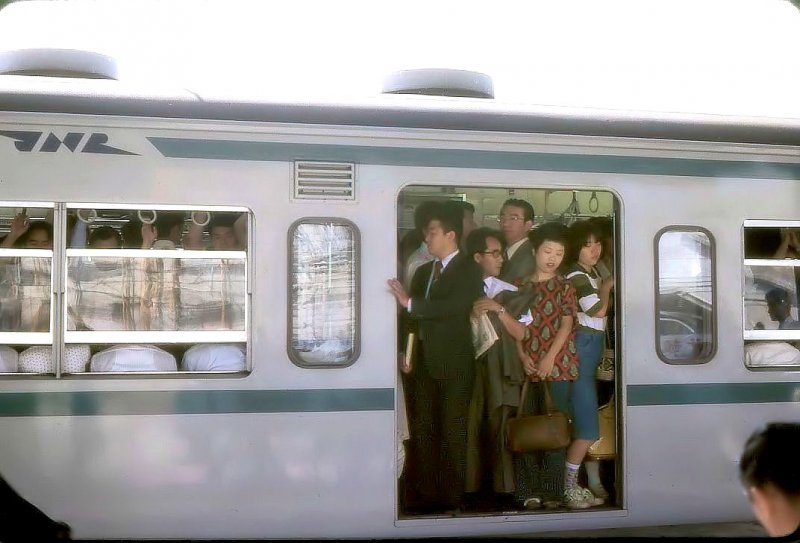Serie 103-1000(JR)/ Tokyo Metro Chiyoda-Linie: Ein Zug, der über die Chiyoda-U-Bahnlinie Tokyo unterqueren wird. In Shin Matsudo, noch　ziemlich weit draussen im Norden von Tokyo, ist der Wagen ganz schön voll; es werden aber noch viel mehr Fahrgäste einsteigen. 5.Juli 1979. JÔBAN-LINIE