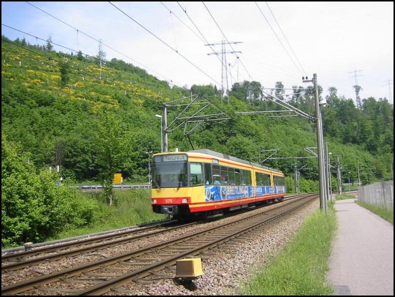 Stadtbahn-Triebwagen 575 ist am 15.05.2006 auf der Linie S11 zwischen Ittersbach und Karlsruhe-Neureut unterwegs. Die Aufnahme erfolgte auf dem Gebiet der Stadt Ettlingen, zwischen den Haltestellen Albgaubad und Spinnerei. Im Hintergrund sind die H�nge des Wattkopf zu sehen.
