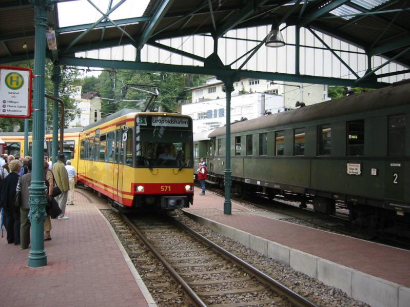 Stadtbahnwagen 571 der Albtal Verkehrs Gesellschaft (AVG), einem Unternehmen des Karlsruher Verkehrs-Verbundes (KVV), fhrt am 22.08.2004 in die Halle des Bahnhofs von Bad Herrenalb ein. Rechts in der Halle ist ein Sonderzug zu sehen, den 50 3539 der Ulmer Eisenbahnfreunde nach Bad Herrenalb gebracht hatte. Die Stadtbahn hat die Wendegleise um das Bahnhofsgebude genutzt und wird kurz darauf ber Ettlingen und Karlsruhe nach Leopoldshafen fahren.