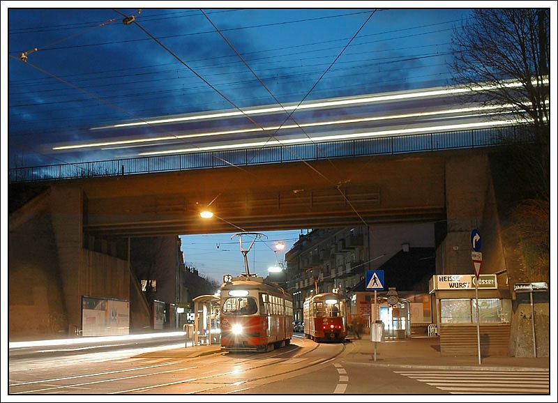Strassenbahntreffen in Wien XII. Rechts oben neben der Brcke befindet sich die S-Bahnstation Hetzendorf. Am Foto begegnen sich zwei Strassenbahnen vom Typ E1 der Linie 62, darber berquert gerade eine Doppelstockgarnitur die Eisenbahnbrcke. Da es der Zufall nicht so haben wollte, dass man gleichzeitig zwei Strassenbahnen und darber einen durchfahrende Doppelstockgarnitur auf ein Bild bannen konnte, besteht dieses Bild aus insgesamt 3 Fotos.