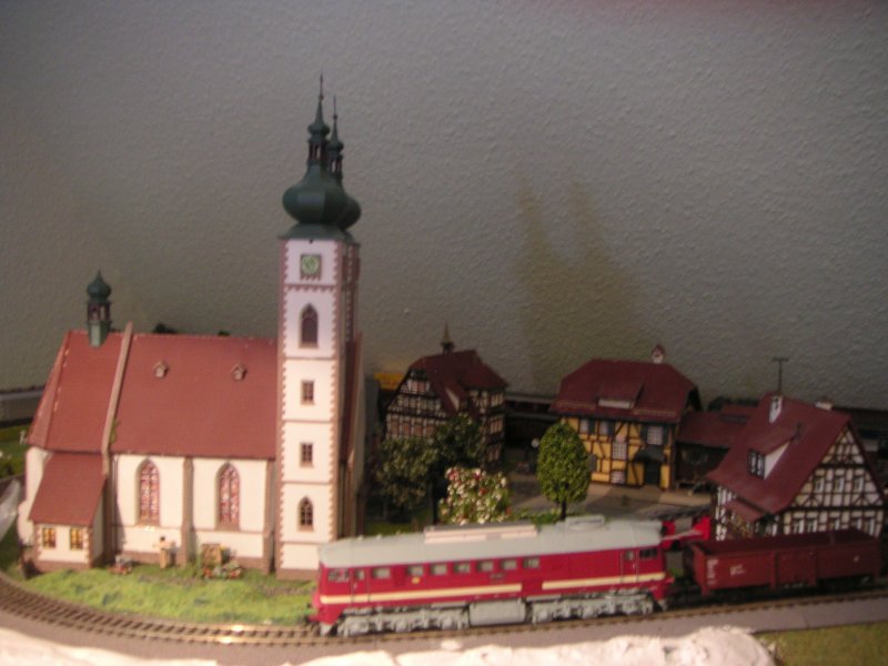 Taigatrommel (von Roco) mit Schttgutzug fhrt an der Kitzlinger Kirche vorbei