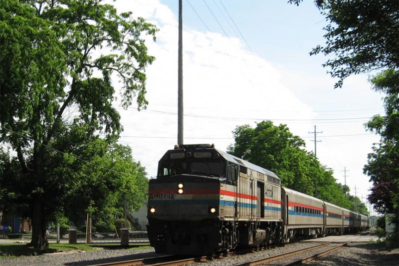 The lead unit, Amtrak 90225, is a former GM-EMD F40PH now converted to an unpowered control cab/baggage car. It leads three passenger cars and Amtrak #27, a GE Genesis P42DC (out of frame), which is providing the motive power. It is crossing West Main Street in Kalamazoo. Wolverine service, train #352, with service from Chicago, Illinois to Pontiac, Michigan, arriving 25 minutes late on 22.06.2006.