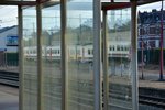 In den Fensterscheiben der Wartehäuschen im Bahnhof Mouscron/Mouskroen spiegeln sich die zahlreichen abgestellten Triebwagen wieder.