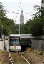 Im Hintergrund der Turm der Liebfrauenkathedrale -

Hier blickt man von Westen auf den 123 Meter hohen Turm. Zwischen Fotostandpunkt und Turm befindet sich die Schelde, der Strom an dem Antwerpen liegt. Es gibt keine Brücken über die Schelde im Stadtbereich, da hier auch noch Seeschiffe verkehren. Um auf die andere Seite, das Linkeroever zu kommen müssen Tunnels benutzt werden. Es gibt einen Straßentunnel, einen Fußgängertunnel, einen Autobahn- und Eisenbahntunnel und den Tunnel der Pre-Metro, aus dem hier eine Hermelijn-Tram der Linie 3 kommt.

Die Tunnelstrecke unter der Schelde hindurch war in der ursprünglichen Pre-Metro Planung gar nicht vorgesehen. Für den Weiterbau des Tunnels zur anderen Scheldeseite musste die bis dahin als Endstation dienende Station Groenplaats, die eine Wendeschleife hatte, in einen doppelstöckige Durchgangsstation umgebaut werden um die in bis zu 31 Meter unter der Wasseroberfläche liegende Tunnelröhren anzuschließen. Die Tunnelstrecke und die daran anschließende Straßenbahnstrecke wurde 1990 eröffnet. Die Straßenbahnstrecke auf dem Linkeroever wurde 2002 dann bis Zwijndrecht verlängert.

24.06.2016 (M) 