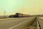 DSB: Am 5. September 1976 fährt die Nohab-Diesellok Mx 1039 mit einem Personenzug in Richtung Thisted. Der Zug befindet sich unweit von der Stadt Struer; im Hintergrund ahnt man Struer, das eine wichtige Bahnstadt ist. - Scan eines Farbnegativs. Film: Kodak Kodacolor II. Kamera: Minolta SRT-101.
