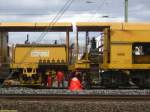 Die Gleisstopfmaschine, die bei der Erneuerung von Gleis 2 am Bahnhof Frankfurt am Main-Niederrad im Einsatz war, hatte am 02.04.2006 offenbar einen Defekt. Die Maschine stand mit laufendem Motor, und die Arbeiter bastelten am unteren Bereich des Fahrzeugs.