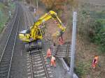 Ein Schienenbagger hebt Schwellen aus dem Schotterbett, damit in diesem Bereich die Gleise um 60 cm.