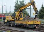 Ein Liebherr Zweiwegebagger von der Firma Leonard Weiss hebt am 15.07.2011 in Stolberg Hbf neben den Gleisen ein Loch aus und schaufelt den Abraum in den mitgefhrten Kleinwagen.