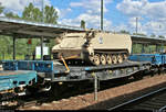 Blick auf einen polnischen vierachsigen Flachwagen der Gattung  Slmmps 443Z  (31 51 4706 148-7 PL-PKPC) von PKP Cargo S.A., beladen mit einem panzerähnlichen Fahrzeug der United States Army, der