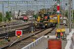 Bahnsteigerneuerung und Bahnbetrieb (||) - Nach der Einfahrt des Railjets erhielt der auf dem Gleis zum Hafenbahnhof wartende Zweiwegebagger A 922 Rail Litronic mit einem Flachwagen freie Fahrt zur Umfahrung von Gleis 3, an dem der Bahnsteig erneuert und ein Aufzug eingebaut wird (Gesicht des Baggerfahrers stark verfremdet). Im Hintergrund befindet sich 185 388-6, die auf Gleisfreigabe wartet, um für einen Fahrtrichtungswechsel die Güterwagen umfahren zu können. Friedrichshafen, 10.07.2023