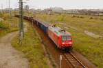 Mit leisem Quietschen und Rumpeln schleicht sich ein langer Gterzug, bespannt mit 145 065 am 05.10.2011 langsam am  Friedhof  des einstigen Rangier-Grobahnhofes Halle/Saale vorbei.