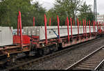 Blick auf einen Drehgestell-Flachwagen der Gattung  Rbns 641  (350 7 066-8 D-DB) der DB, beladen mit langen Betonteilen, der in einem gemischten Gz mit 185 120-3 DB eingereiht ist und den Bahnhof