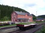 Das Empfangsgebude des Bahnhofs Schnheide Sd. Im Vordergrund ein in der Aufarbeitung befindlicher Flachwagen des FHWE. (26.07.09)