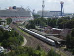 Blick auf den Warnemünder Hauptbahnhof: Im Vordergrund ein ICE Baureihe 411; hinten rechts die Warnow-Werft, hinten links das Kreuzfahrt-Schiff  Norwegian Gateway .