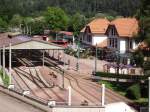 Blick auf den Sdkopf des Bahnhofs Bad Herrenalb, im Sommer 2010. Im Vordergrund die Umsetz- und Abstellgleise, dahinter die historische Bahnhofhalle, des ehemaligen Baden-Badener Stadtbahnhofs und links davon das gut erhaltene und genutzte Empfangsgebude aus dem Jahr 1889. 