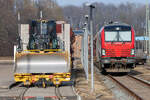 Siemens VECTRON DUAL MODE Lok 248997 mit Schotterwagen abgestellt in Bergen auf Rügen. Auf dem Nachbargleis steht eine CATERPILLAR Planierraupe der D3 Serie. - 07.03.2026 - Am Gleisbogen aufgenommen.

