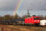 Mit Regenbogen im Hintergrund fährt 185-019-6 der Sonne in Richtung Bremerhaven Hbf entgegen.