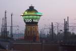 Am frhen Morgen (6 Uhr) verlsst der RE 3604 Halle/Saale Hbf nach Hannover und fhrt zuerst einmal noch am ehem. Wasserturm in Halle vorbei, der hier beleuchtet, Werbung fr den lokalen Zoo macht.
Halle, der 13.4.09