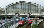Bahnhofshallen sind immer beeindruckend, das gilt natürlich auch für die des Hamburger Hauptbahnhofes. Am 06.07.2023 verläßt ein S-Bahn-Triebwagen der Baureihe 474 die Halle, daneben die 101 061-0 mit einem IC.