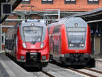 Ein Elektrotriebzug (442 843) und eine von 143 193-1 geschobene Doppelstockeinheit der DB Regio warten auf die Abfahrt. (Stralsund, August 2021)