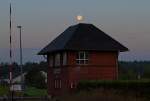 Untergehender Vollmond steht ber dem Stellwerk.