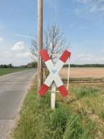 Ein altes Andreaskreuz mit Rahmen zeigt noch heute dass hier immer noch ein Bahnübergang ist.