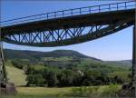 Ein Fischbauchträger über der Landschaft und auch ein Zug -     Blick unter dem Biesenbach-Viadukt hindurch zum Epfenhofener Viadukt.