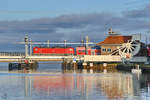Eine mir unbekannte Elektrolokomotive der Baureihe 112 schiebt den aus Stralsund kommenden RE3 über die Eisenbahnbrücke in Anklam. (November 2020)
