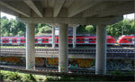 Hinten eine S-Bahn -    Fünf Gleise, teilweise auf verschiedenen Ebenen werden hier durch eine Straßenbrücke überspannt.