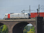 Die Elektrolokomotive 185 699-7 befährt die Hochfelder Eisenbahnbrücke, so gesehen Ende August 2022 in Duisburg.