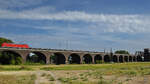 Die Elektrolokomotive 185 144-3 zieht einen leeren Coilzug über die Hochfelder Eisenbahnbrücke, so gesehen Ende August 2022 in Duisburg.