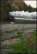 PRESS 86 1744-1 dampfte am frühen Morgen des 18.04.2026 mit dem exPRESSzugreisen-Sonderzug Chemnitz - Aue - Karlsbad (Karlovy Vary) in Einsiedel an der Stützmauer der Zwönitz entlang.