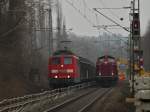 Am 03.03.2012 steht 212 370-1 der EfW-Verkehrsgesellschaft mit einem vollgeladenen Flachwagenzug mit Betonschwellen auf der KBS 480 bei Aachen Rothe Erde und wird von zwei Baggern entladen. Auf dem freien Gleis nebenan fhrt 151 029-6 mit einem Gterzug nach Aachen West.