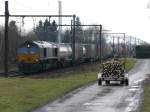 Grosstransporter kreuzt Kleintransporter. Eine Class 66 von DLC zieht einen Containerzug in Richtung Antwerpen. Auf der Strasse zieht ein Einwohner einen mit Brennholz beladenen kleinen Anhnger. Aufgenommen am 20/02/2010 in 's Herenhelderen.