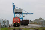298 334-4 holt einen mit Kohle beladenen Zug aus dem Rostocker Seehafen ab. Das Bild entstand von einem Bahnübergang einer öffentlichen Straße aus bei stehendem Zug. (14.04.2026)