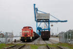 298 334-4 holt einen mit Kohle beladenen Zug aus dem Rostocker Seehafen ab. Das Bild entstand von einem Bahnübergang einer öffentlichen Straße aus bei stehendem Zug. (14.04.2026)