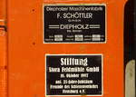 Das Fabrikschild und das Schild einer Stiftung an der Rangierlok im Bf.