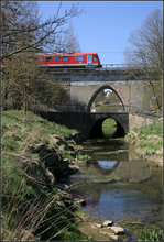Ein Fisch(?) stört die Spiegelung -    Bahn- und Straßenbrücke über den Seebach in Rot am See an der Taubertalbahn.