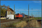 Mit einem gemischten Güterzug rollt 145 032-0 an der Blockstelle Braschwitz vorbei, die auch gleichzeitig den örtlichen Bahnübergang bedient.