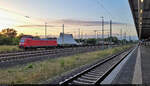 Mit leeren sechsachsigen Flachwagen der Bundeswehr kommt 145 053-5 in Magdeburg Hbf am Abend der Sonne entgegengefahren.