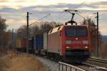 Der Himmel glht. 152 074-1  entflieht  am 12.02.11 mit einem langen Containerzug Hafeneinwrts diesem  Inferno . Aufgenommen in Hamburg-Moorburg.