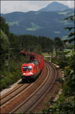 182 023 (9180 6182 023-2 D-DB) legt sich mit einem Holzganzzug bei Kiefersfelden in die Kurve.