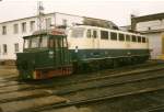 Akkuschleppfahrzeug 107 und die Hamburger 110 379 im Mrz 1999 im Bh Rostock vor dem stromlosen Lokschuppen.