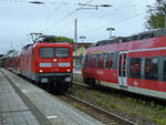 Die Elektrolokomotive 112 188 zieht eine RE-Doppelstockgarnitur in Richtung Rostock und spiegelt sich dabei im Triebzug 442 123.