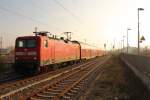 Die Sonne kämpft sich durch den Nebel, während der RE 18510 mit der Zuglok 112 123 in den Bahnhof Oranienburg einfährt, so am 27.11.2014 gesehen.